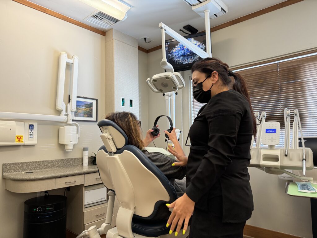 A dental assistant offering noise-canceling headphones to a patient in our Palo Alto office for a stress-free experience.