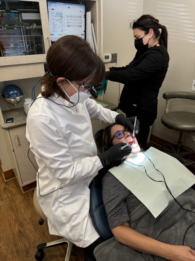 A dentist in Palo Alto performing a clinical periodontal exam and gum treatment for a patient in a modern dental operatory.
