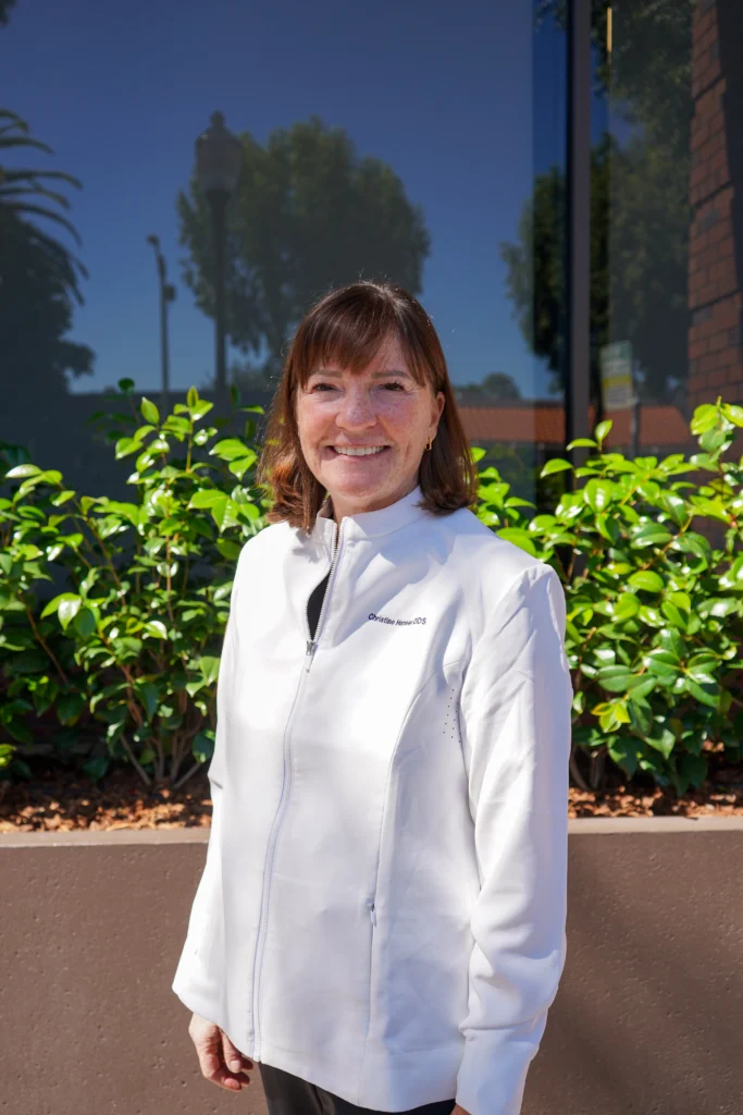 Dr. Christine Hansen smiling warmly outside her modern Palo Alto dental office facility.