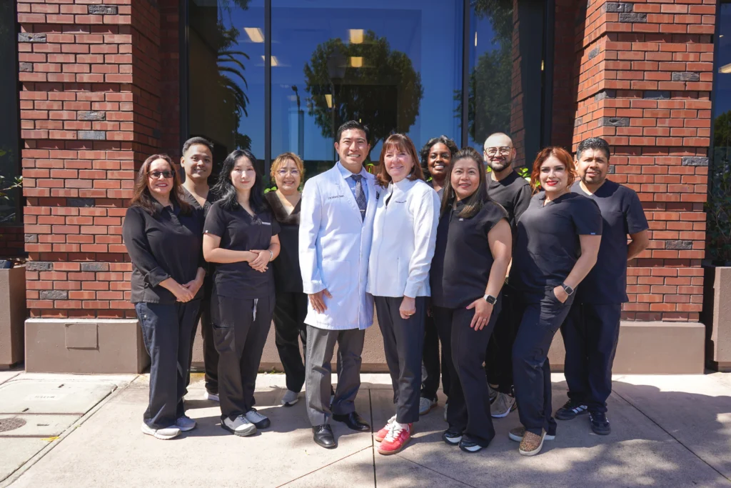 Dr. Harry Tseng, Dr. Christine Hansen, and the friendly dental hygiene and administrative team smiling together at their Palo Alto office.