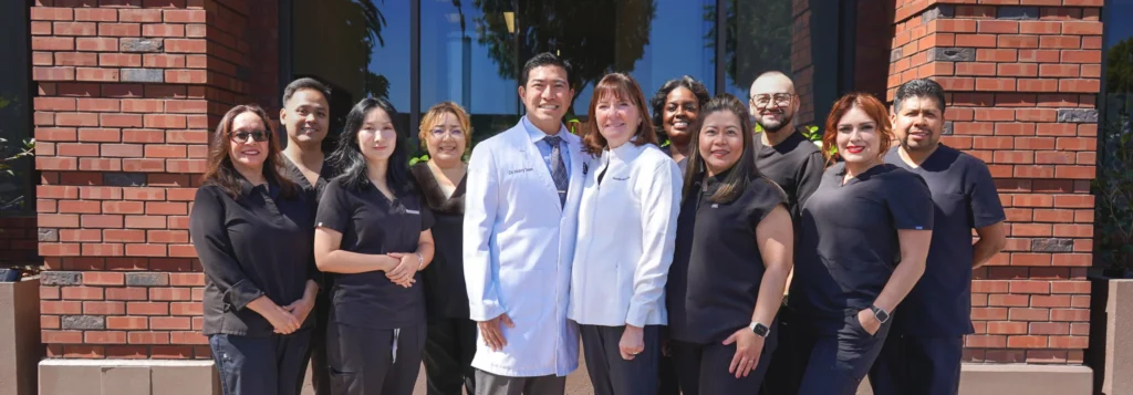 Dr. Harry Tseng, Dr. Christine Hansen, and the friendly dental hygiene and administrative team smiling together at their Palo Alto office.
