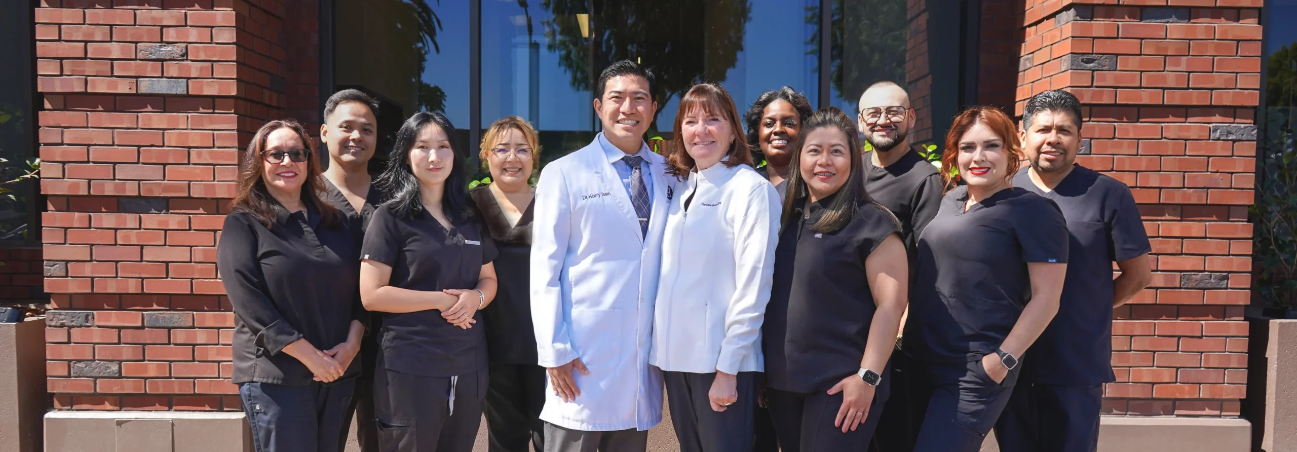 Dr. Harry Tseng, Dr. Christine Hansen, and the friendly dental hygiene and administrative team smiling together at their Palo Alto office.